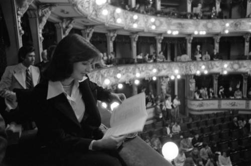 A woman reading a program while sitting in the balcony
