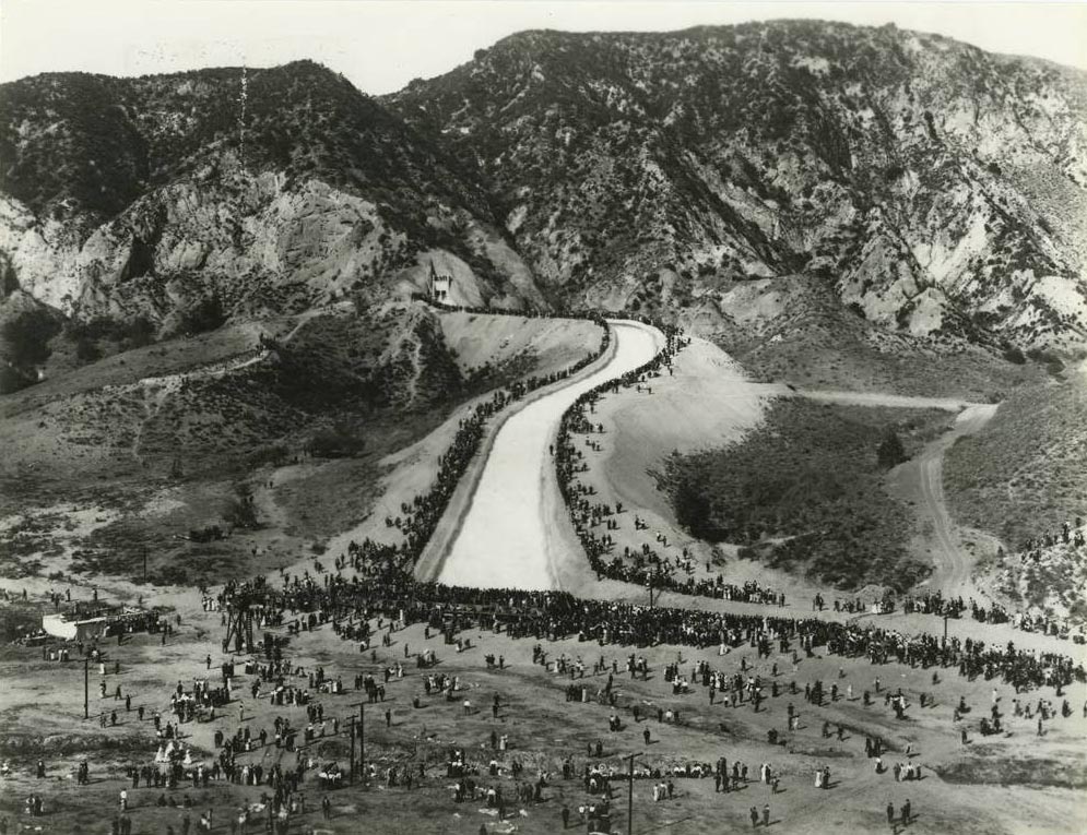 Wide view of Cascades aqueduct outlet with water flowing down the mountain into the valley. Crowds of people on the sides of the channel.