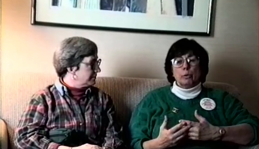 Two women discussing a topic while sitting on a couch.